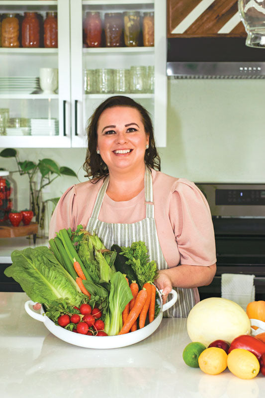 Amy Cross in her kitchen holding a bowl of fresh produce