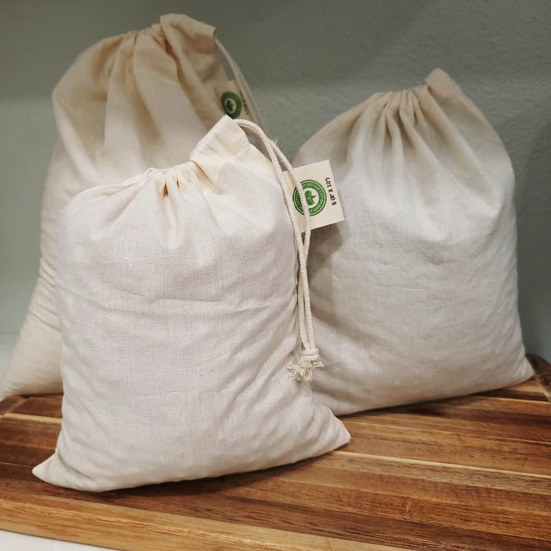 3 muslin bags filled with the draw-string tops closed, sitting on a wooden cutting board